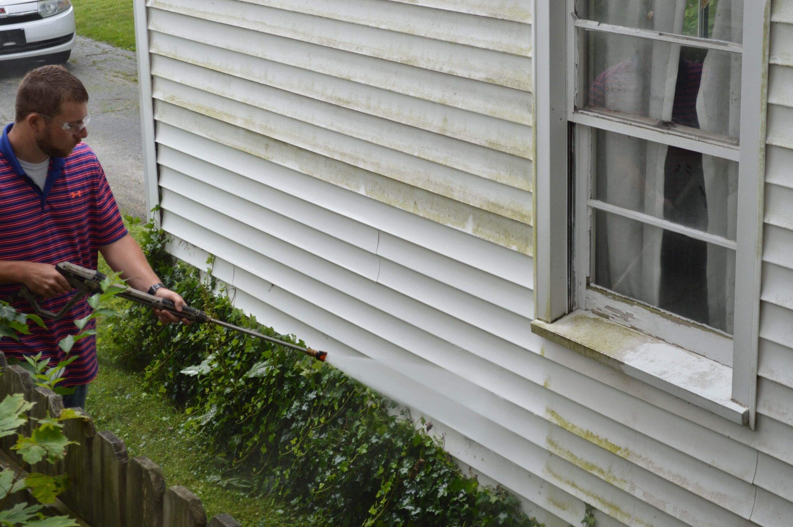A man uses an EC Jet to clean vinyl siding.