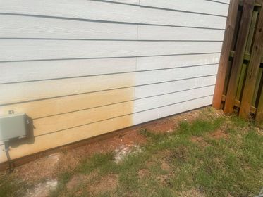Red clay stains have been cleaned from the side of a building.